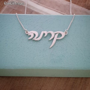 May include: A silver necklace with a Hebrew name pendant. The pendant is in a cursive script style.