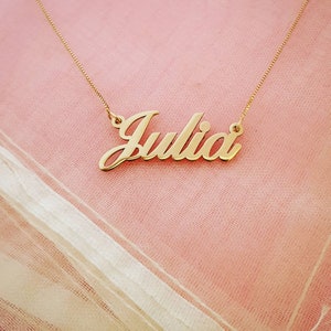 May include: A gold necklace with the name "Julia" spelled out in a cursive font.