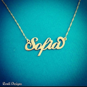 May include: A gold necklace with the name "Sofia" spelled out in a cursive font.
