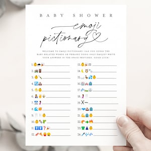 May include: A printable baby shower game called "Emoji Pictionary". The game features 24 emoji icons and blank lines for players to write down their guesses. The text on the card reads "Baby Shower Emoji Pictionary".