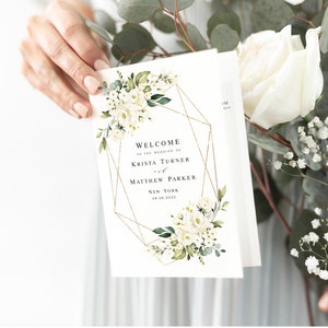 May include: A white wedding program with gold geometric shapes and white flowers. The text reads "Welcome to the wedding of Krista Turner & Matthew Parker, New York, 09.08.2022".