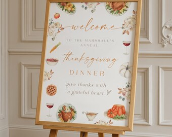 May include: A wooden easel displaying a Thanksgiving dinner welcome sign. The sign features floral and food illustrations, with text that reads "welcome" and "Thanksgiving Dinner." The sign is in a light wood frame.