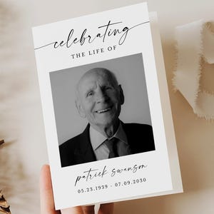 May include: A white memorial card featuring a black and white photograph of an elderly man. The card's text reads "Celebrating the Life of" and the name "Patrick Swanson" with dates 05.23.1939 - 07.09.2030. A fern and white ribbon are in the background.