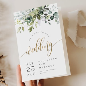 May include: A white wedding invitation card with gold script that reads "Welcome to our Wedding". The card is decorated with green foliage and the names Elizabeth and Matthew. The date is August 23rd.
