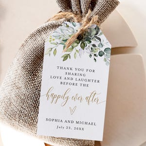 May include: A burlap gift bag tied with twine, featuring a white tag with floral accents. The tag reads "Thank you for sharing love and laughter before the happily ever after" with a couple's names and a date.