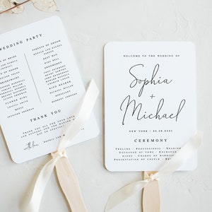 Op de afbeelding: Twee witte bruiloftsvaandels met ivoorkleurige lintjes. De linker vaande is een lijst met de bruiloftsgasten en de rechter vaande heeft de tekst "Welkom op de bruiloft van Sophia + Michael" en de datum "New York | 22.08.2023".