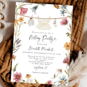 Peut inclure: Une invitation à une baby shower avec des illustrations florales à l'aquarelle. L'invitation présente le texte "Nesting Party" et les détails de l'événement. Un hochet en bois et un body marron sont également dans l'image.