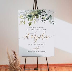 May include: A wedding sign with a watercolor floral design. The sign says "Assigned seats are not our style, sit anywhere that makes you smile, Melissa & Richard".