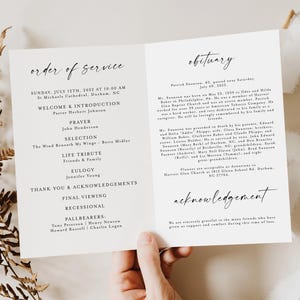 Pode incluir: Um programa fúnebre dobrado com o texto "Ordem de Serviço" e "Obituário" em escrita elegante. O programa inclui detalhes como a data, hora, local e nomes dos envolvidos. Uma mão segura o programa, com folhagens secas e uma fita branca ao fundo.