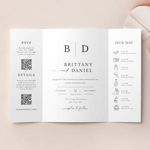 May include: A white wedding invitation, folded into three panels, with the names "Brittany and Daniel" in elegant script. The invitation includes a schedule of events, RSVP details, and QR codes for more information.