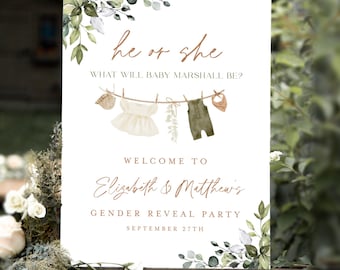 May include: A white sign on a wooden easel with the text "he or she" and "What will baby Marshall be?" in elegant script. The sign welcomes guests to Elizabeth & Matthew's gender reveal party on September 27th.