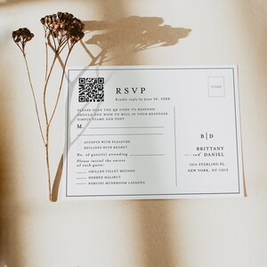 May include: A white RSVP card with a black border. The card has a QR code, a space for the guest's name, and a section for the guest to choose between accepting or declining the invitation. The card also includes a space for the guest to indicate the number of guests attending and to choose their entree. The card has the text "RSVP" and "Kindly reply by June 20, 20XX". The card also has the text "Please scan the QR code to respond. Should you wish to mail in your response, simply stamp and post." The card also has the text "M." and "B | D" and the text "BRITTANY & DANIEL" and the text "1314 STERLING PL. NEW YORK, NY 11213". The card also has the text "GRILLED FILLET MIGNON", "HERBED HALIBUT", and "PORCINI MUSHROOM LASAGNA".