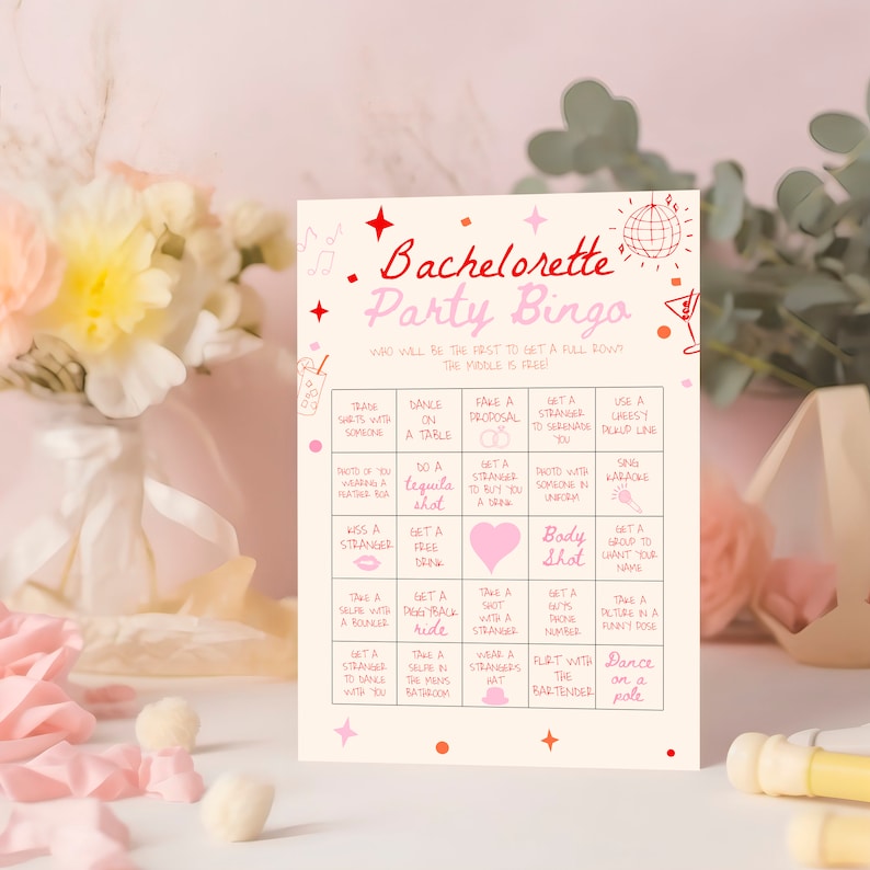 May include: A pink and red bachelorette party bingo card with a pink disco ball and a martini glass graphic. The card has a grid of 25 squares with different activities to complete, such as "trade shirts with someone", "dance on a table", "fake a proposal", "get a stranger to serenade you", "use a cheesy pickup line", "photo of you wearing a hat/boa", "do a tequila shot", "get a stranger to buy you a drink", "photo with someone in uniform", "sing karaoke", "kiss a stranger", "get a free drink", "body shot", "get a group to chant your name", "take a selfie with a bouncer", "get a piggyback ride", "take a shot with a stranger", "get a guy's phone number", "take a picture in a funny pose", "get a stranger to dance with you", "take a selfie in the men's bathroom", "wear a stranger's hat", "flirt with the bartender", "dance on a pole".