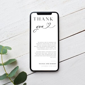 May include: A white thank you card with black text on a smartphone screen. The text reads "THANK you" with a heart symbol. The card also includes a message expressing gratitude for attending a baby shower. The message reads "We would like to express our heartfelt gratitude to you for making our baby shower such a special and unforgettable moment. Your presence, kind words, and good wishes mean a lot to us. We were deeply touched by your attention and care. Your gift was not only very generous but also infused with your thoughtfulness and love. Nicole and Robert"