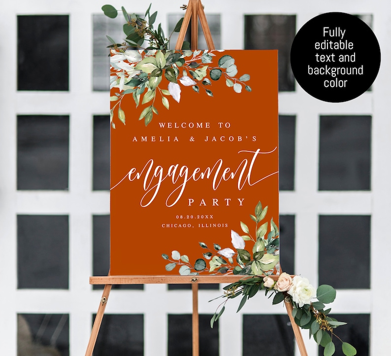 Puede incluir: Un cartel de bienvenida para una fiesta de compromiso con un fondo naranja &oacute;xido y texto blanco. El texto dice "Bienvenido a Amelia & Jacob's Engagement Party 08.20.20XX Chicago, Illinois". El cartel est&aacute; decorado con vegetaci&oacute;n acuarela.