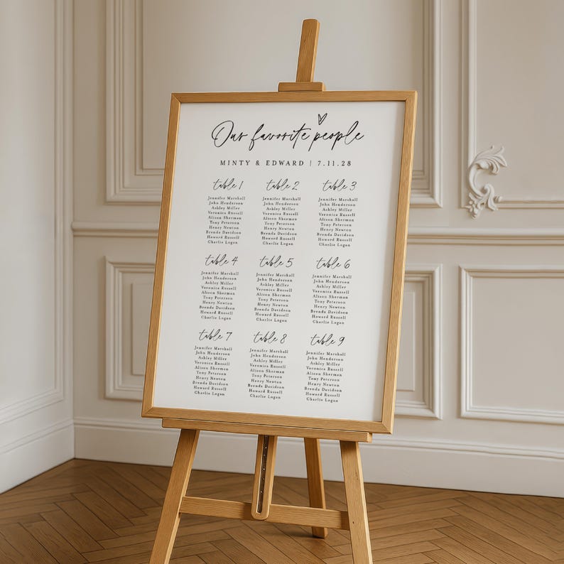 Framed minimalist wedding seating chart reading "Our Favorite People" in elegant script, presented on a wooden easel in a classic indoor venue. Perfect for printable or editable Canva templates for reception decor.