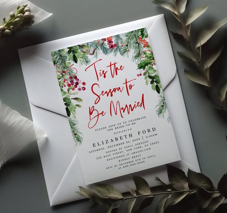 May include: A white invitation card with the text "Tis the Season to Be Married" in red script, framed by watercolor greenery and red berries. The card is inside a white envelope, perfect for a winter wedding.