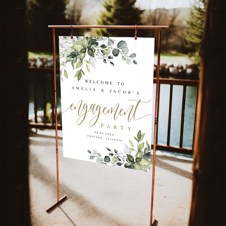 Puede incluir: Un cartel de bienvenida blanco con follaje verde acuarela y letras doradas. El cartel dice "Bienvenido a Amelia & Jacob's Engagement Party 08.20.20XX Chicago, Illinois".