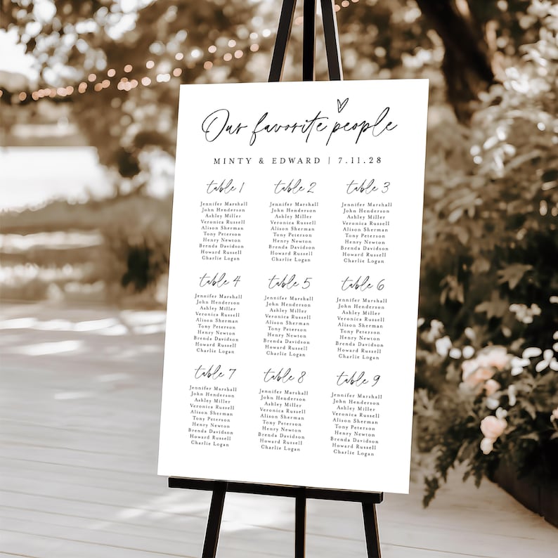 Chic outdoor "Find Your Seat" wedding seating chart sign on black easel, surrounded by soft lighting and floral decor. Scripted headers and modern typography make this Templett.com editable chart perfect for receptions.