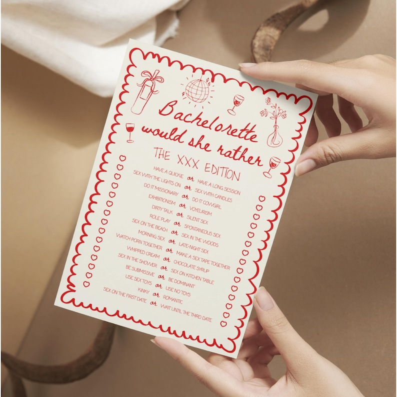 May include: A white card with red decorative border and text, held by hands. The card reads "Bachelorette would she rather" with a list of playful questions. The card has illustrations of a champagne bottle, disco ball, and wine glasses.