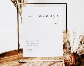 Może przedstawiać: Złota rama z białym znakiem z napisem "mimosa BAR" w eleganckim czarnym skrypcie. Poniżej instrukcje: "Pour the bubbly, Add some juice, Top with fruit, enjoy." Tło zawiera suszone kwiaty i drewnianą tacę.