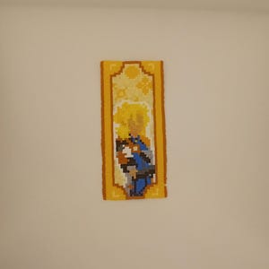 May include: A yellow and blue beaded wall hanging featuring a pixelated image of a character with blonde hair.