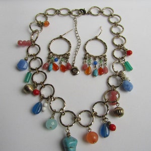 May include: A gold chain necklace with multiple colorful beads and charms, including turquoise, blue, red, orange, and pink. The necklace is paired with matching earrings with similar charms.