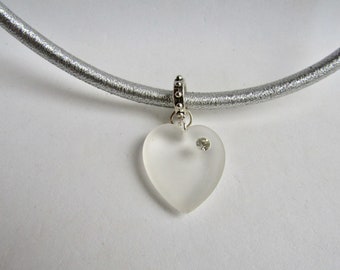 May include: A silver elastic necklace with a clear glass heart charm that has a small clear rhinestone in the center.