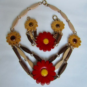 May include: A wooden necklace with a layered design featuring brown and beige wooden links and red and yellow flower accents.
