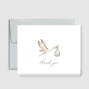 May include: A white greeting card with a watercolor illustration of a stork carrying a bundle. The words "thank you" are written in a delicate script below the stork. The card is paired with a light gray envelope.
