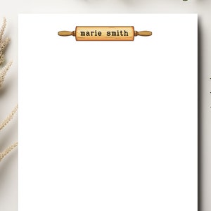 May include: A white notepad with a wooden rolling pin with the text "marie smith" printed on it.