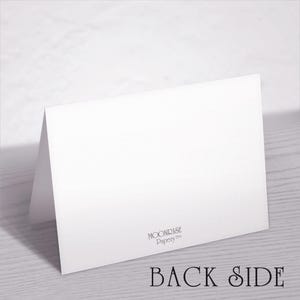May include: A white folded card with the text "BACK SIDE" in a serif font. The card is angled, revealing the back and a portion of the front. The Moonrise Papery&trade; logo is visible.