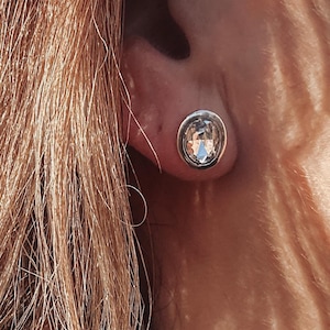 Puede incluir: Un par de pendientes de plata con piedras ovaladas transparentes.