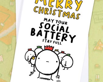 May include: A white Christmas card with the text "MERRY CHRISTMAS" in yellow and "MAY YOUR SOCIAL BATTERY STAY FULL" in black. The card features cartoon characters with crowns.
