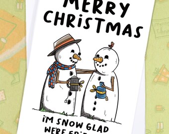 May include: A white Christmas card with the words "MERRY CHRISTMAS" in large black letters. Two snowmen are featured, one wearing a hat and scarf, the other with a bird on its head. The text "I'M SNOW GLAD WE'RE FRIENDS" is at the bottom.
