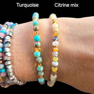 May include: Two beaded bracelets on a person's wrist. The bracelet on the left is turquoise and the bracelet on the right is a mix of citrine colors.