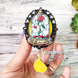 May include: Hand painted stained glass charm featuring a red rose in a glass dome with the text "'til the last petal falls". The charm is attached to a yellow dress charm.