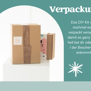 May include: Two brown cardboard boxes, one large and one small, are displayed on a white surface. The larger box has brown tape and a small label. Text in German reads "Verpackung" and describes the packaging of a DIY kit.