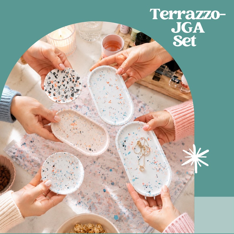 Peut inclure: Un ensemble Terrazzo-JGA compos&eacute; de quatre plateaux d&eacute;coratifs de formes ovales et circulaires. Les plateaux pr&eacute;sentent des bases blanches, beiges et bleu clair avec des motifs mouchet&eacute;s multicolores en noir, orange et bleu. Un plateau contient un collier.