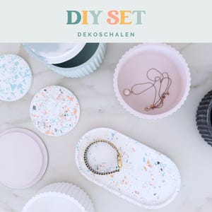 Puede incluir: Un kit DIY SET DEKOSCHALEN que incluye varias bandejas y recipientes circulares y ovalados en rosa pastel, blanco y negro. Algunos art&iacute;culos tienen un patr&oacute;n de terrazo moteado, mientras que otros son de colores s&oacute;lidos con bordes estriados o lisos.