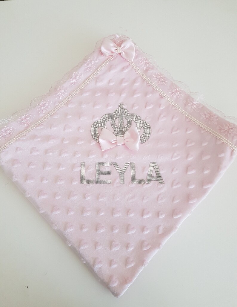 May include: Pink baby blanket with a crown and the name "LEYLA" embroidered in silver rhinestones.