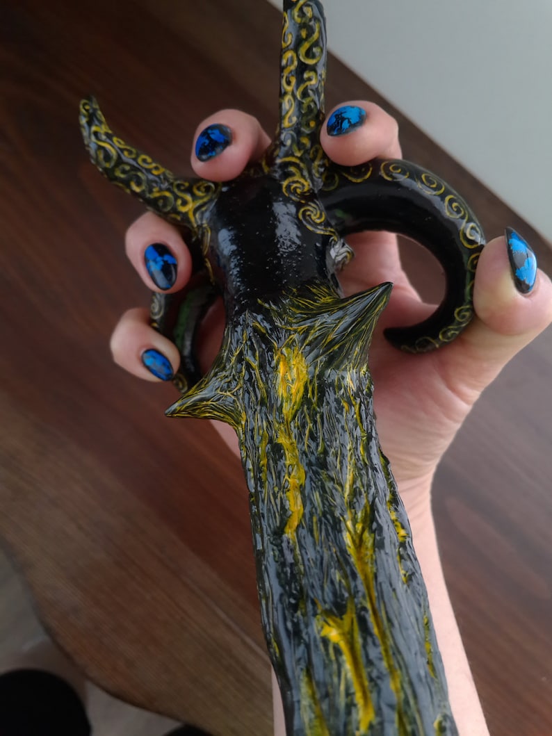 Pu&ograve; includere: Una spada decorativa nera e dorata con un design dettagliato. La spada ha una superficie testurizzata e una punta appuntita.