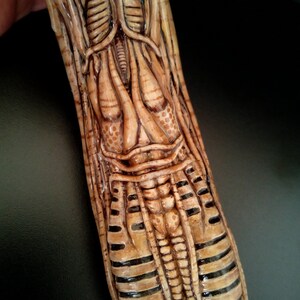 May include: A detailed, close-up view of a sculpted, beige and brown alien creature with a segmented body and intricate details. The creature's body is covered in a network of veins and tubes.