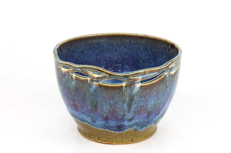 May include: A blue and brown ceramic bowl with a decorative cut-out design around the rim.