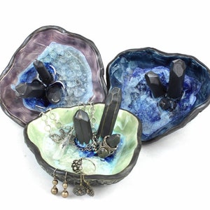 May include: Three ceramic ring dishes with a geode design. Each dish features black crystal accents and a different color glaze: purple, blue, and green.