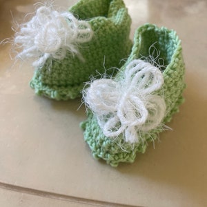 Bottines pour bébé vert clair tricotées à la main avec des nœuds blancs