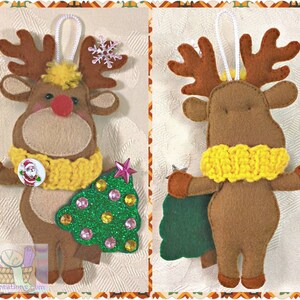 Puede incluir: Un adorno de reno de fieltro marr&oacute;n con una bufanda de punto amarilla, sosteniendo un &aacute;rbol de Navidad de fieltro verde con purpurina rosa y dorada. El reno tiene la nariz roja y un copo de nieve blanco en sus cuernos.