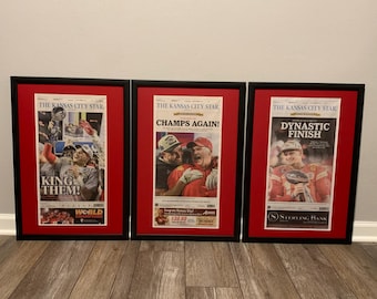May include: Three framed newspaper front pages from The Kansas City Star, celebrating the Kansas City Chiefs' Super Bowl victory. The headlines read "King Them!" "Champs Again!" and "Dynastic Finish".
