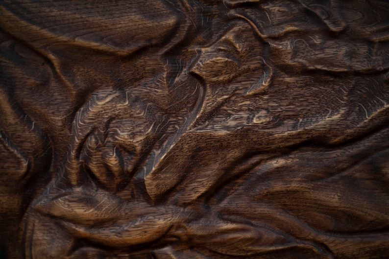 May include: Close-up of a richly textured, dark brown wooden surface. The wood grain is visible, with a pattern of flowing, organic shapes and deep grooves. The surface has a natural, aged appearance.