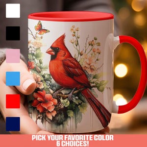 May include: A white ceramic mug with a red rim and handle. The mug features a colorful illustration of a cardinal bird perched on a branch with flowers. The text "PICK YOUR FAVORITE COLOR 6 CHOICES!" is printed below the image.